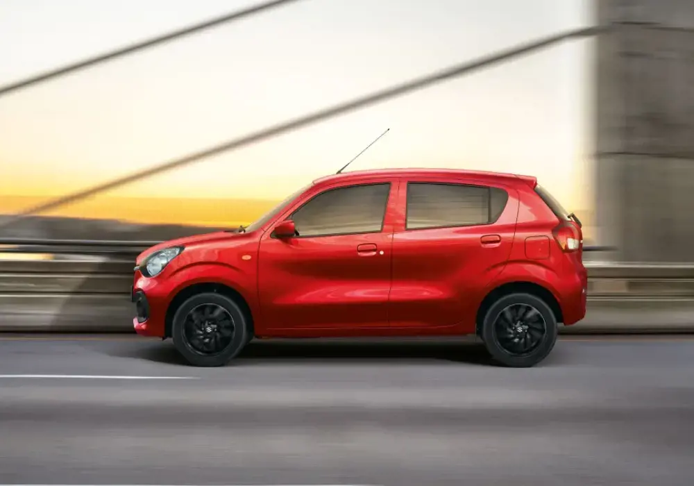 Imagen lateral de un Suzuki Celerio rojo conduciendo por una carretera.